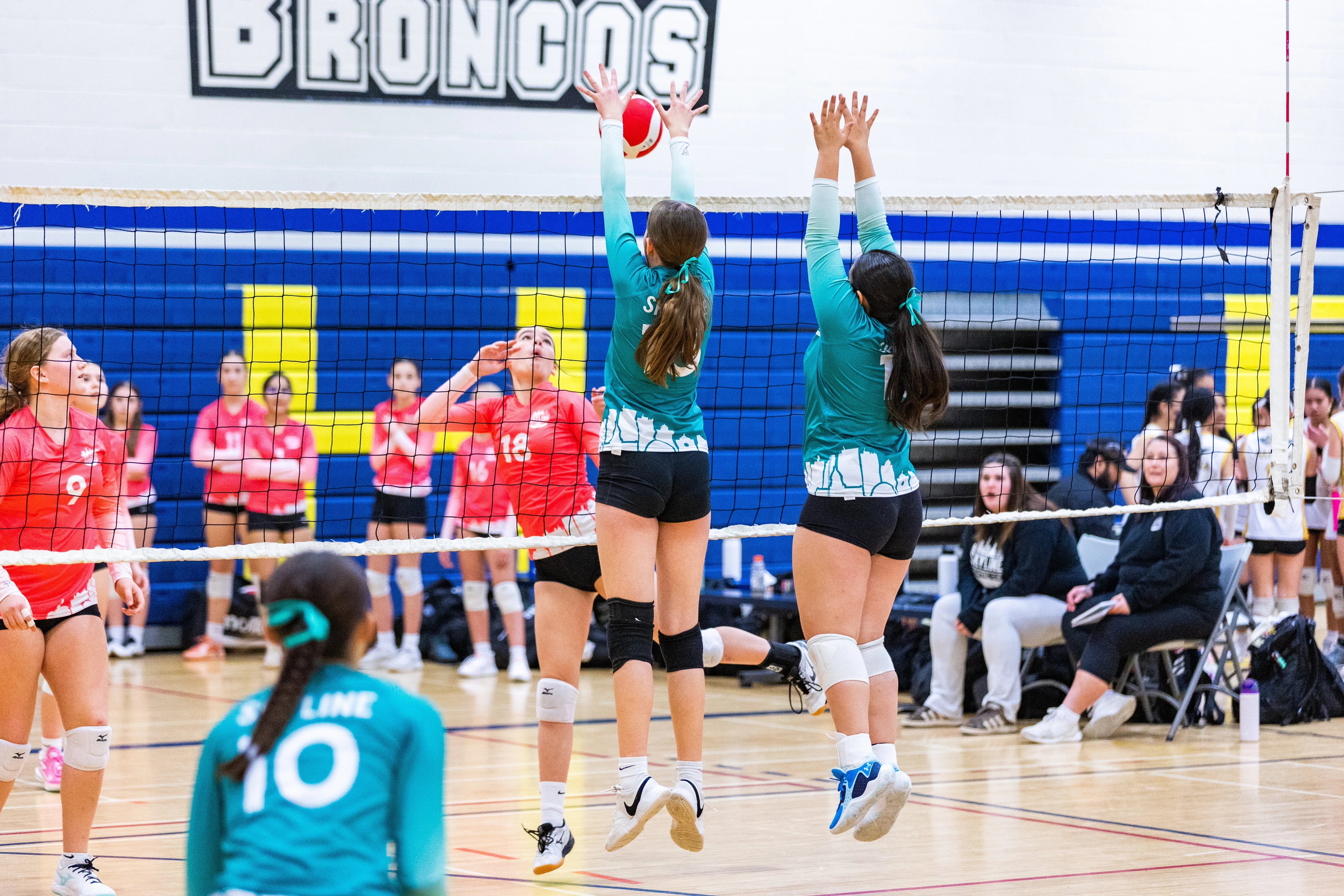 Two Skyline volleyball athletes blocking at the net in competition