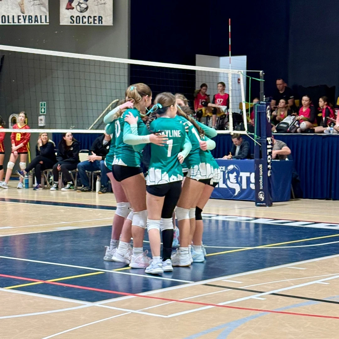 Skyline volleyball team celebrating together in a huddle at a tournament